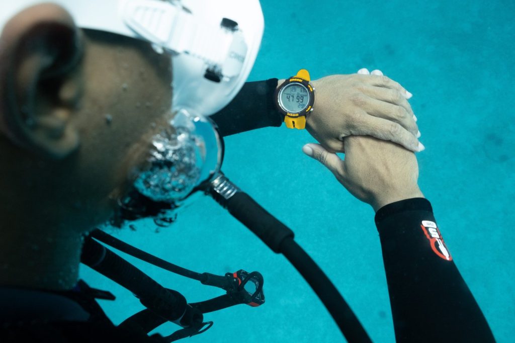 Plongeur consultant sa montre-ordinateur Cressi Neon sous l’eau