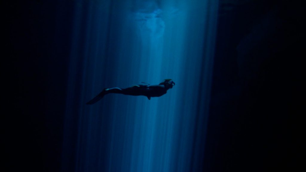 Silhouette d’une apnéiste dans un puits de lumière sous l’eau, scène du film Nos âmes libres